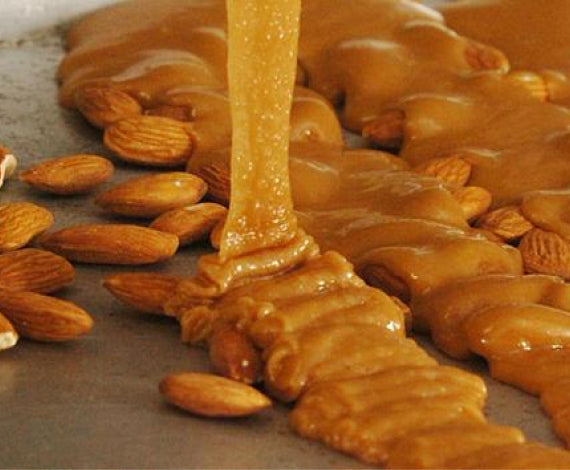 Pouring Toffee over oven roasted almonds